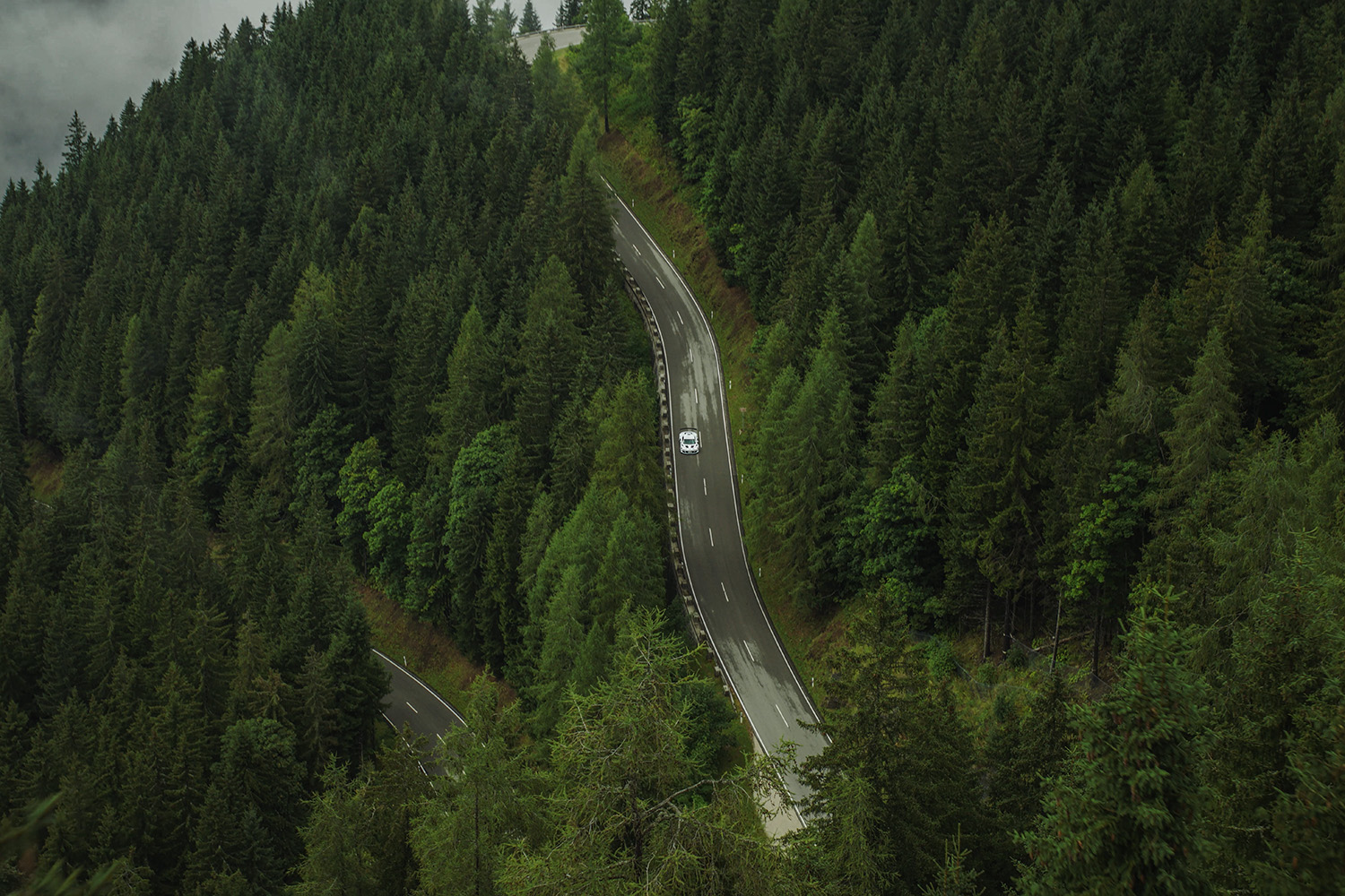 Bird's eye view of a black and white XGT on a road between dense forest
