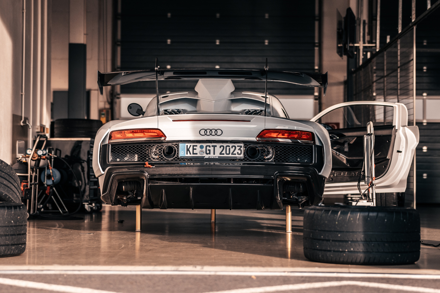 Black and white XGT from the rear view while changing tyres on the lifting platform in the pit