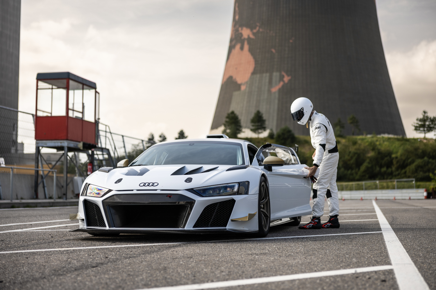 black and white XGT azs the side front view on race track with racing driver next to it