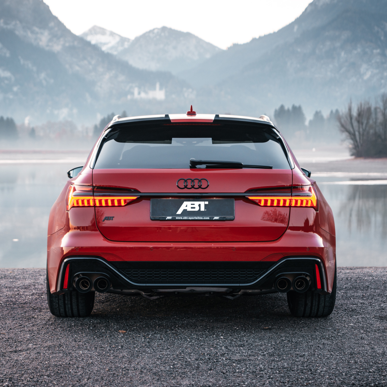 Red RS6-S from the rear view in front of a lake with a mountain panorama