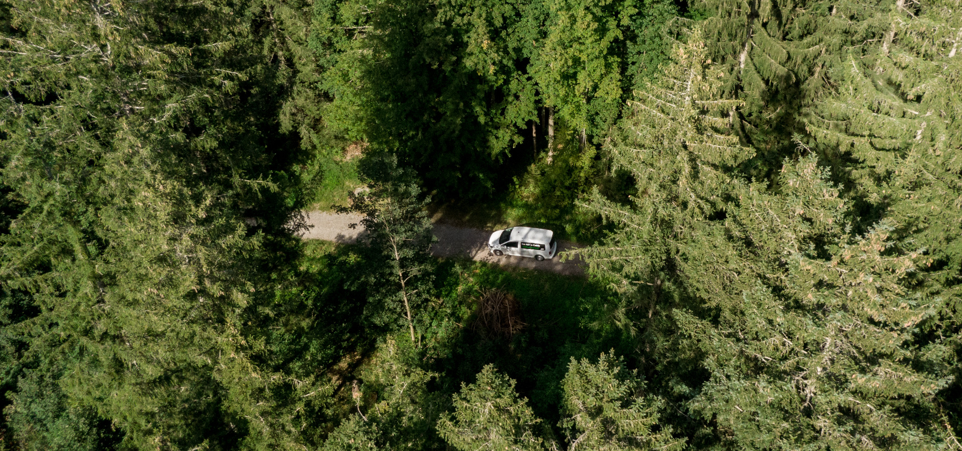 Drone image of an ABT E-Caddy on a dirt track in the forest