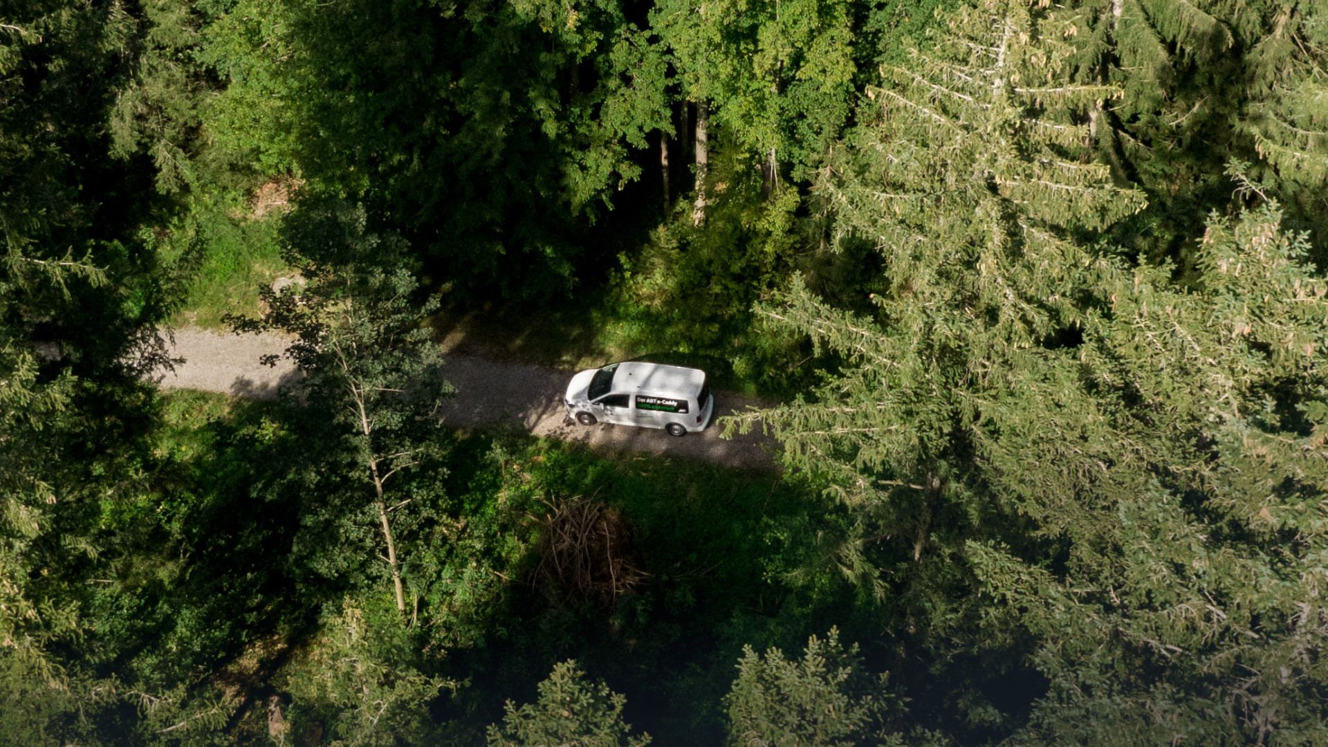 Drone image of an ABT E-Caddy on a dirt track in the forest
