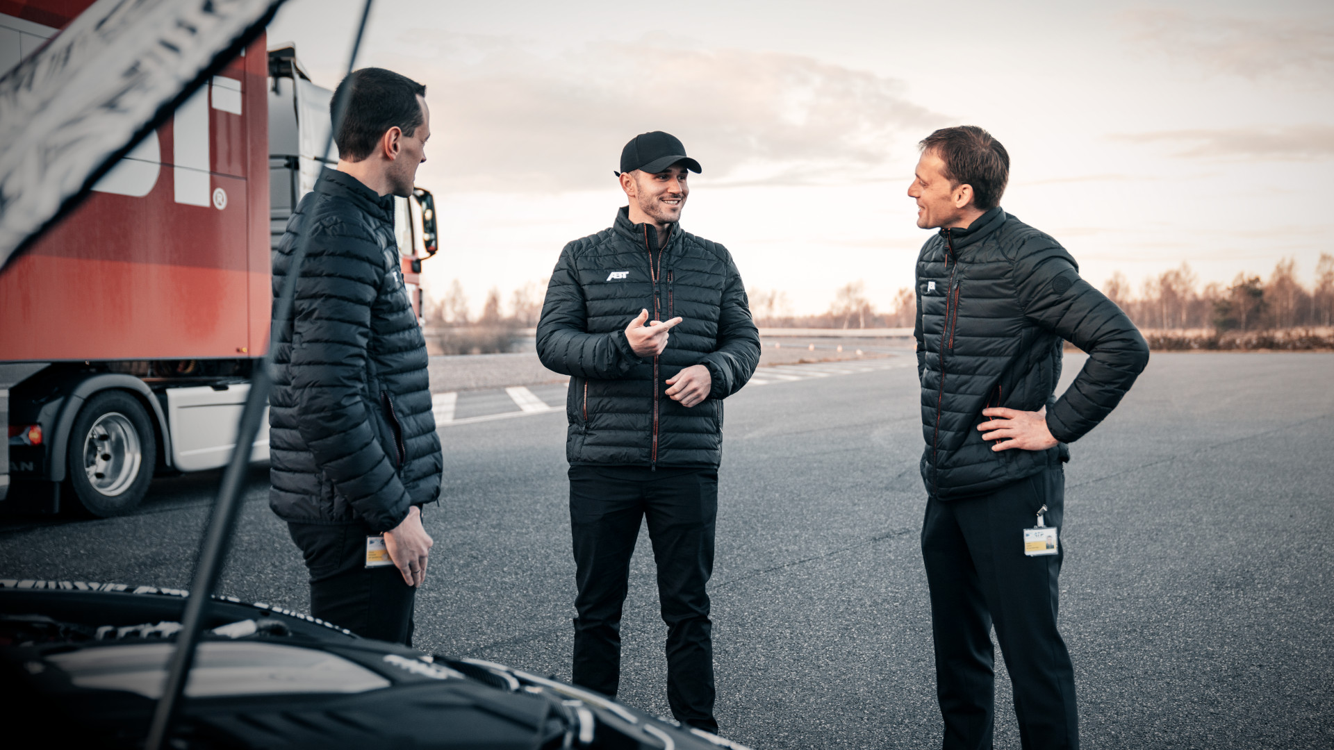 Daniel Abt with two employees in front of an open bonnet